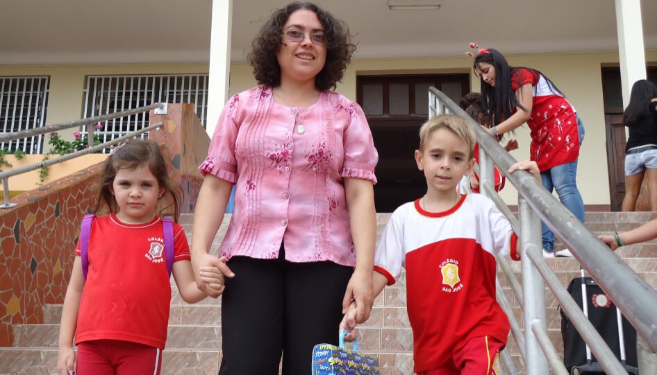 Mulher em uma escada, segurando as mãos de duas crianças.