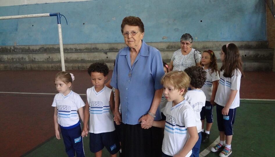 Senhora da Comunidade Irmã Ivone Drummond conduzindo um grupo de crianças.