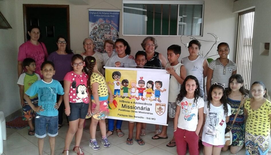 Grupo de mulheres e crianças. No centro, as crianças seguram um cartaz.