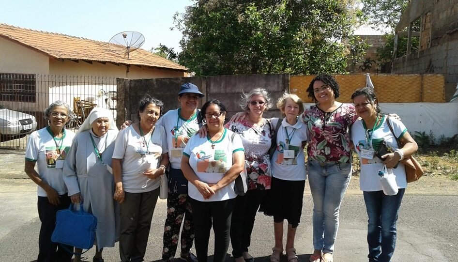 Nove mulheres abraçadas na rua.