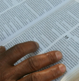 Mão em uma bíblia, simbolizando a reflexão bíblica Buscando as raízes do Deuteronômio.